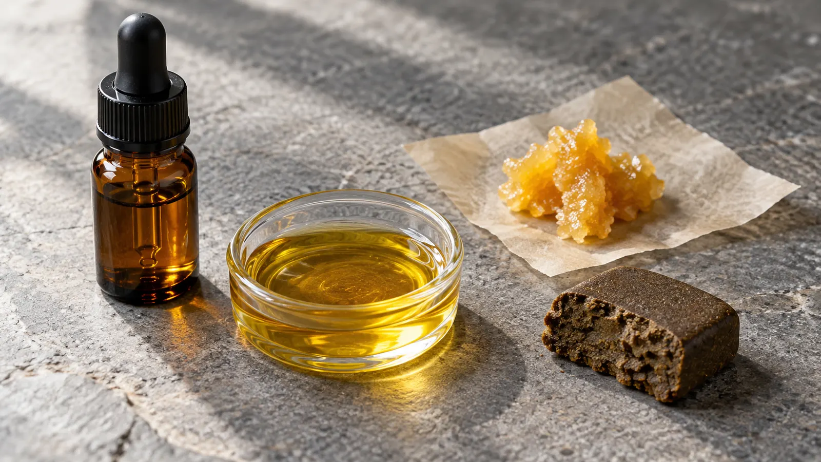 Kenevir yağı, altın rengi wax, preslenmiş haşiş ve taş bir yüzey üzerinde etiketsiz bir damlalıklı şişe.