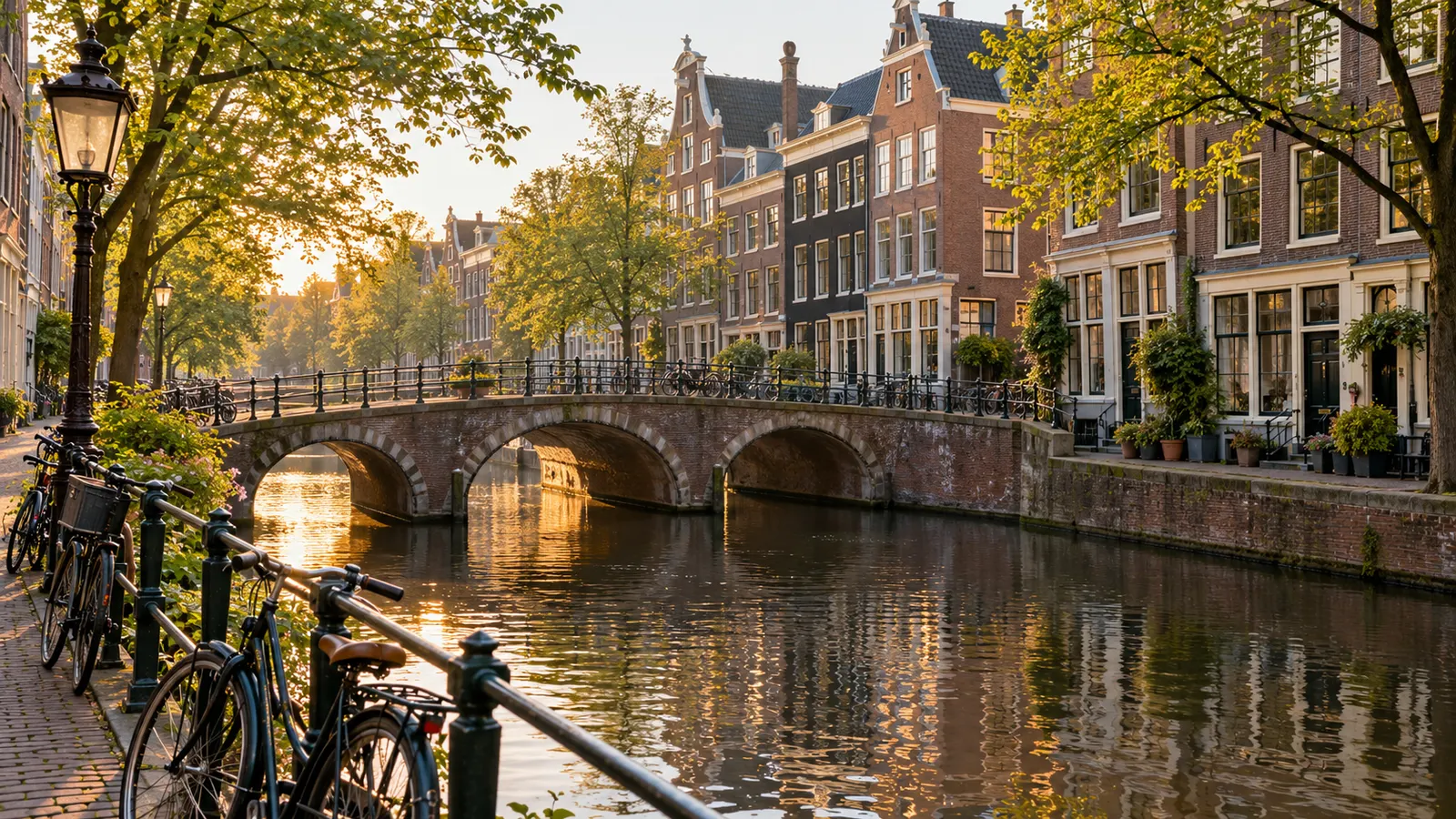 Murstenshuse langs kanalen og parkerede cykler langs en stille kanal i Amsterdams Jordaan-kvarter.