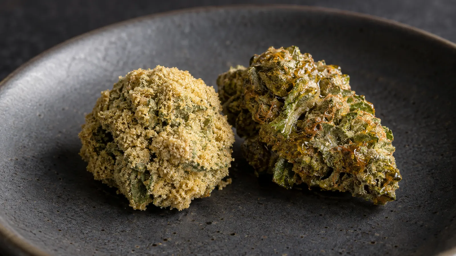 En cannabistop med kiefbelægning og en top med ravfarvet harpiksbelægning hviler på en mørk keramiktallerken.